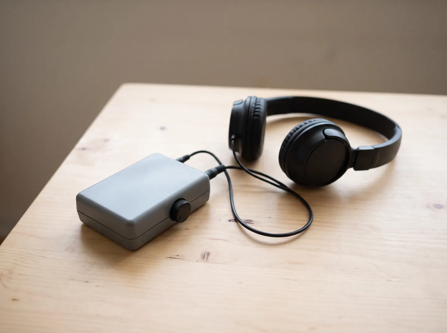 A small handheld loop listener connected to a pair of headphones on a wooden table